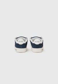 Mornje plave suede tenisice s bijelim gumiranim potplatima. Imaju zaobljen oblik i "etnies" oznaku na peti i jeziku. Glatka tekstura.