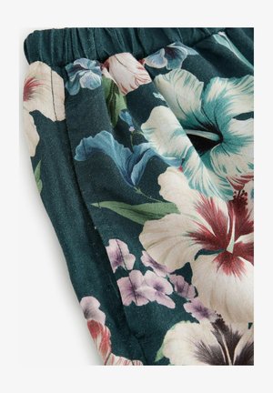 Kvetinová potlač s veľkými bielymi, ružovými a modrými kvetmi na tmavozelenom pozadí, s nariaseným pásom a textúrovaným povrchom.
