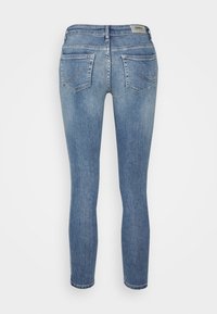 Jeans skinny in denim blu chiaro con una texture liscia, design a cinque tasche e dettagli di cucitura discreti sui taschini posteriori.