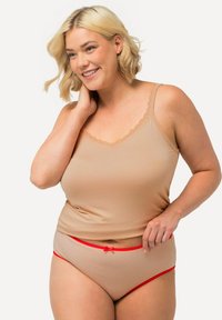 Beige tanktop met kantafwerking en bijpassende beige slip met rode tailleband en strikdetail, beide van een zachte, gladde stof.