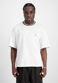 Camiseta de algodón blanca con mangas cortas y corte relajado. Presenta un sutil estampado "BERLÍN" en el pecho y un diseño liso.