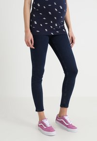 Top azul marino con estampado, jeans ajustados azul oscuro y zapatillas de gamuza rosa con cordones blancos. El diseño notable incluye una silueta ajustada y un estilo casual.