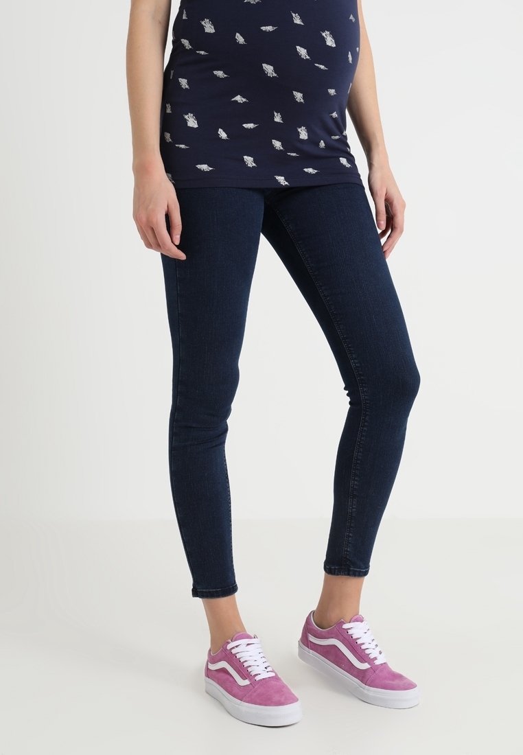 Top azul marino con estampado, jeans ajustados azul oscuro y zapatillas de gamuza rosa con cordones blancos. El diseño notable incluye una silueta ajustada y un estilo casual.