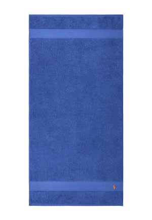 Asciugamano da bagno in cotone blu con design a tinta unita, caratterizzato da una stretta striscia in rilievo vicino a ciascuna estremità e un piccolo logo arancione nell'angolo inferiore.