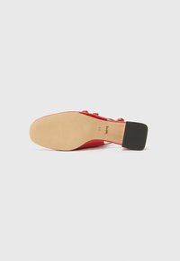 Rote Lackleder-High-Heels mit quadratischem Absatz und glatter Textur; verfügt über vier goldfarbene Knöpfe an der Seite.