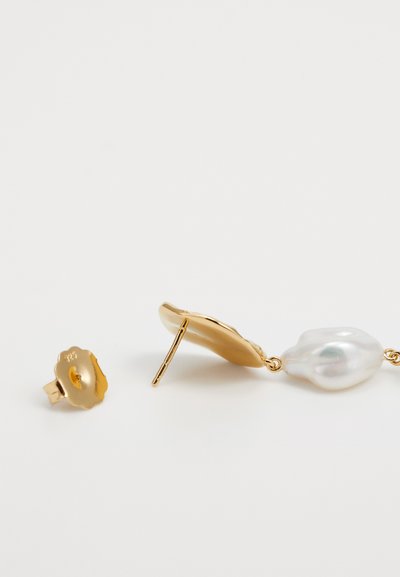 Goldene Ohrringe mit einem strukturierten Blumendesign und einer großen, unregelmäßig geformten Perle, die ein glänzendes Finish und filigrane Details zur Schau stellen.