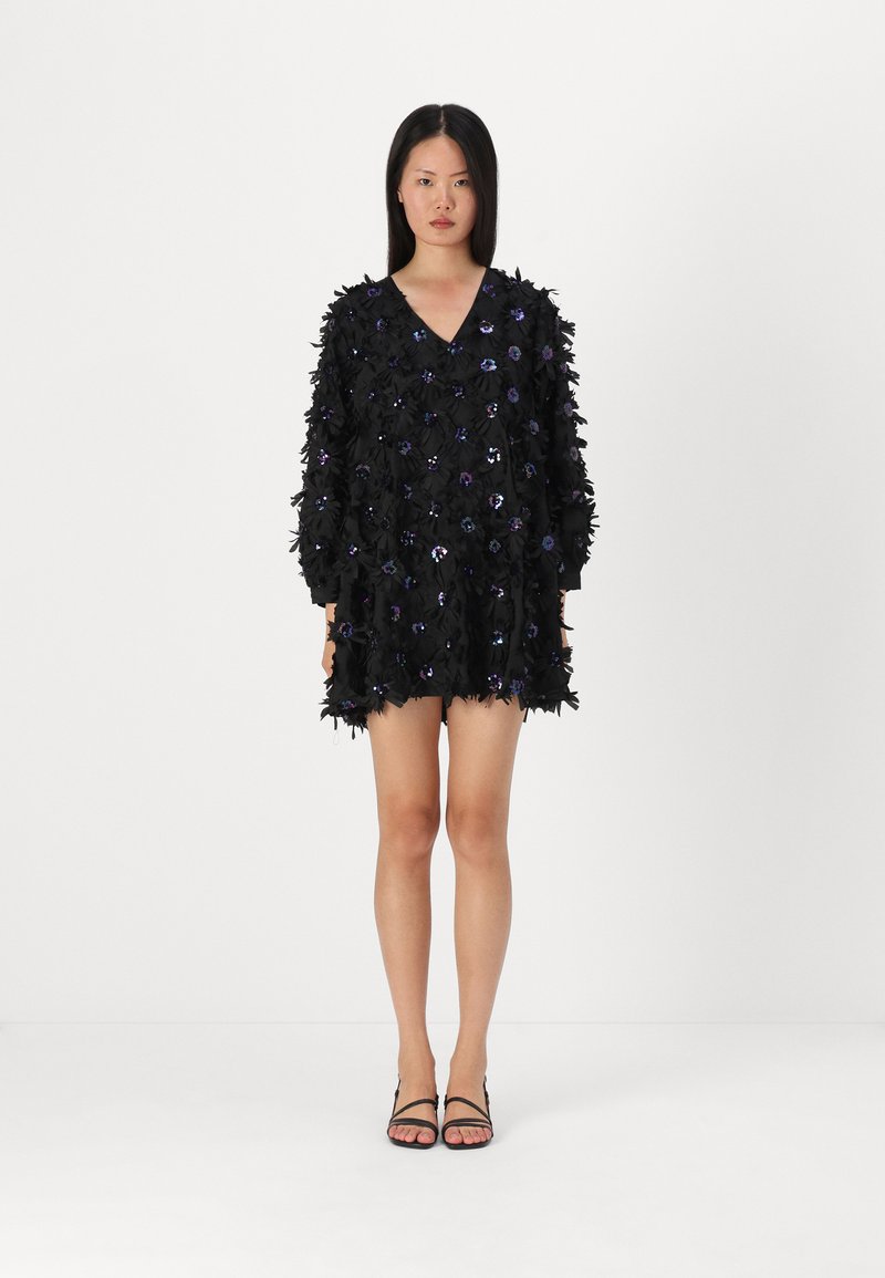 Vestido preto com aplicações florais e lantejoulas, apresentando um decote em V profundo e mangas longas, tecido texturizado e um corte solto.