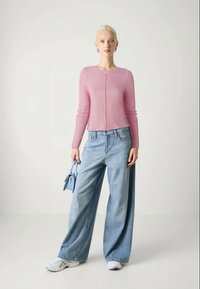 Heled roosa sooniline särk, lühike lõige, koos laia säärega siniste teksastega. Modell hoiab käes väikest sinist käekotti, jalas valged tossud.