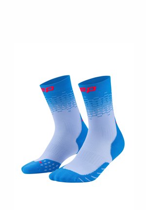 Blue and white athletic crew socks with red logo, featuring a gradient pixel pattern and textured grip dots on the soles.
