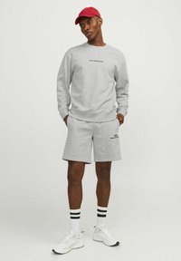Gray sweatshirt and shorts made of soft fabric, featuring black text. White sneakers with black accents, and white socks with black stripes.
