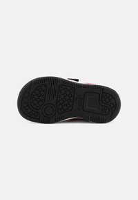 Semelle de chaussure en caoutchouc noir avec des motifs de grip texturés, formes circulaires et hexagonales, arborant un logo de marque bien visible.