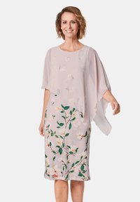 Leichtes Blumenkleid mit einem fließenden, transparenten Überzug und kurzen Ärmeln. Die Farben umfassen zartes Rosa, Grün und weiße Blumenmuster.