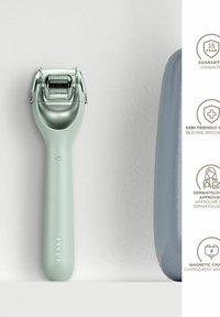 Grön silikonrulle med en texturerad metallever, strömlinjeformad handtag och magnetisk laddningsfunktion. Ytterligare grå förvaringsbas visas.
