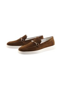 Bruna mockaläders loafers med vita gummisulor och silverfärgad hängsmyckesdetalj på vampen, visade i sidovy mot en vit bakgrund.