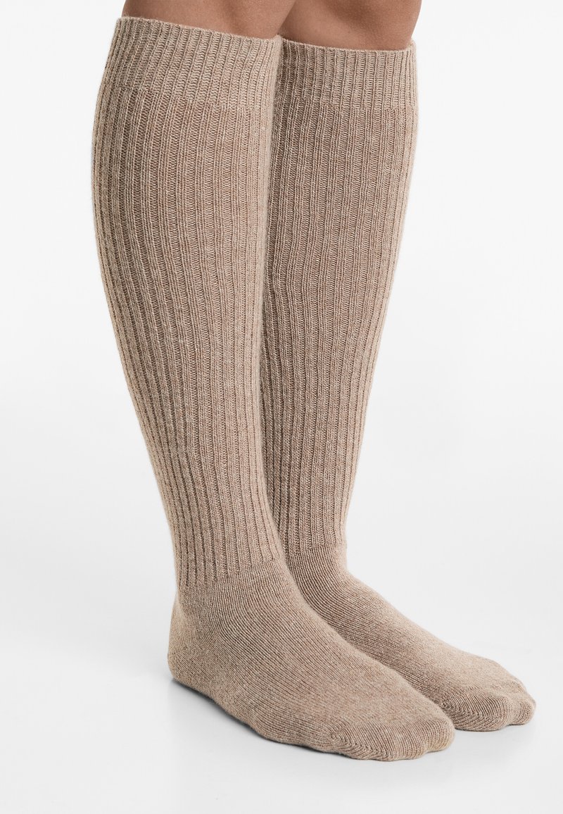 Knæhøje sokker i en lys beige nuance, med ribbet tekstur, blødt materiale og sømløst tådesign for komfort.