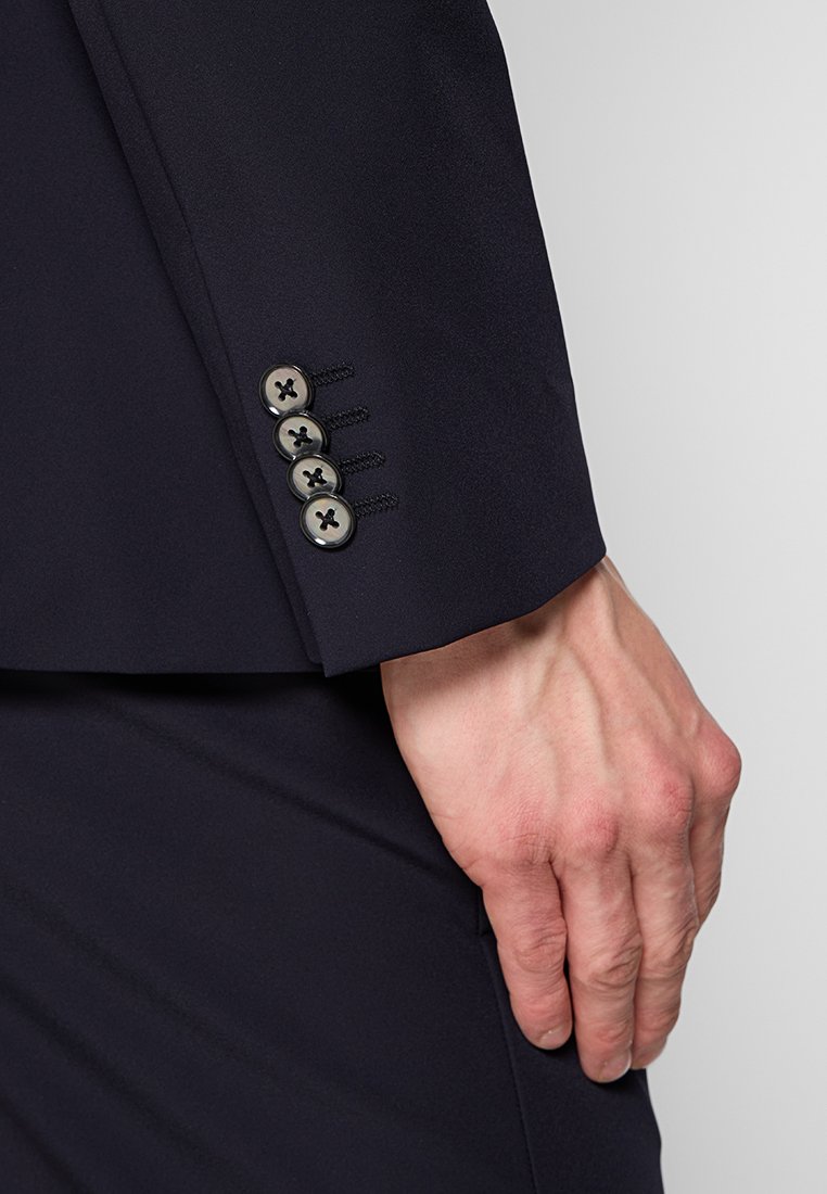 Marineblazer-Ärmel mit fünf dekorativen Knöpfen; glattes Gewebe mit leichtem Glanz; taillierte Passform, die den Handgelenkbereich betont.