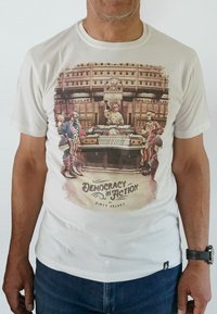 White t-shirt featuring a colorful clown graphic with the text "Democracy in Action" in a vintage style, showcasing vibrant colors and cartoonish details.