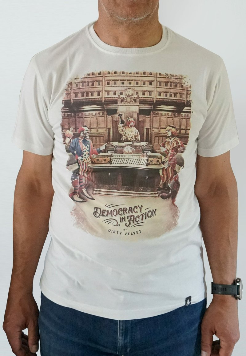 White t-shirt featuring a colorful clown graphic with the text "Democracy in Action" in a vintage style, showcasing vibrant colors and cartoonish details.