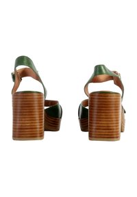 Sandalias de tacón alto de cuero verde con un tacón de madera apilado, correa trasera y diseño de punta abierta; textura suave y estilo minimalista.