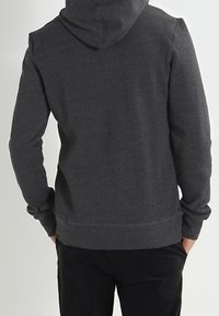 Sudadera con capucha de color gris oscuro con una textura suave, puños y dobladillo acanalados, y un bolsillo canguro en la parte delantera.