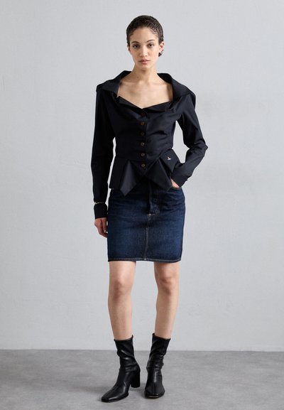 Μαύρη εφαρμοστή μπλούζα με μεγάλο γιακά και καφέ κουμπιά, συνδυασμένη με τζιν φούστα. Μαύρες μπότες μέχρι τον αστράγαλο ολοκληρώνουν την εμφάνιση. Λείες υφές.