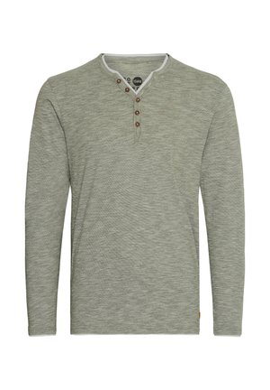 Langermet henley skjorte i strukturert lysegrønn stoff med en 3-knapps placket og rund halslinning. Merkbare brune knapper og subtilt mønster.
