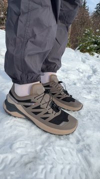 Salomon Trailrunning-Schuhe mit braunem und schwarzem Farbschema, atmungsaktivem Mesh-Obermaterial, Schnürsystem und robuster Sohle für Grip auf Schnee.