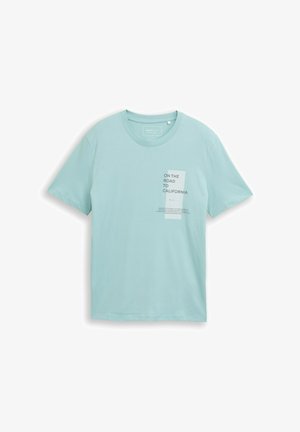 Jasnoniebieska bawełniana koszulka z krótkim rękawem, z grafiką na przedzie, która zawiera elementy tekstowe oraz prostokątną łatkę.