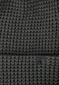 Dzianina w kolorze ciemnoszarym z fakturowanym wzorem w kratkę. Posiada małą czarną metkę z napisem "Bickley Mitchell" na krawędzi.