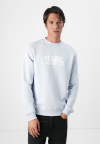Sudadera azul claro hecha de una mezcla de algodón. Presenta un cuello redondo, puños acanalados y un destacado logo en blanco "KARL LAGERFELD" en el frente.