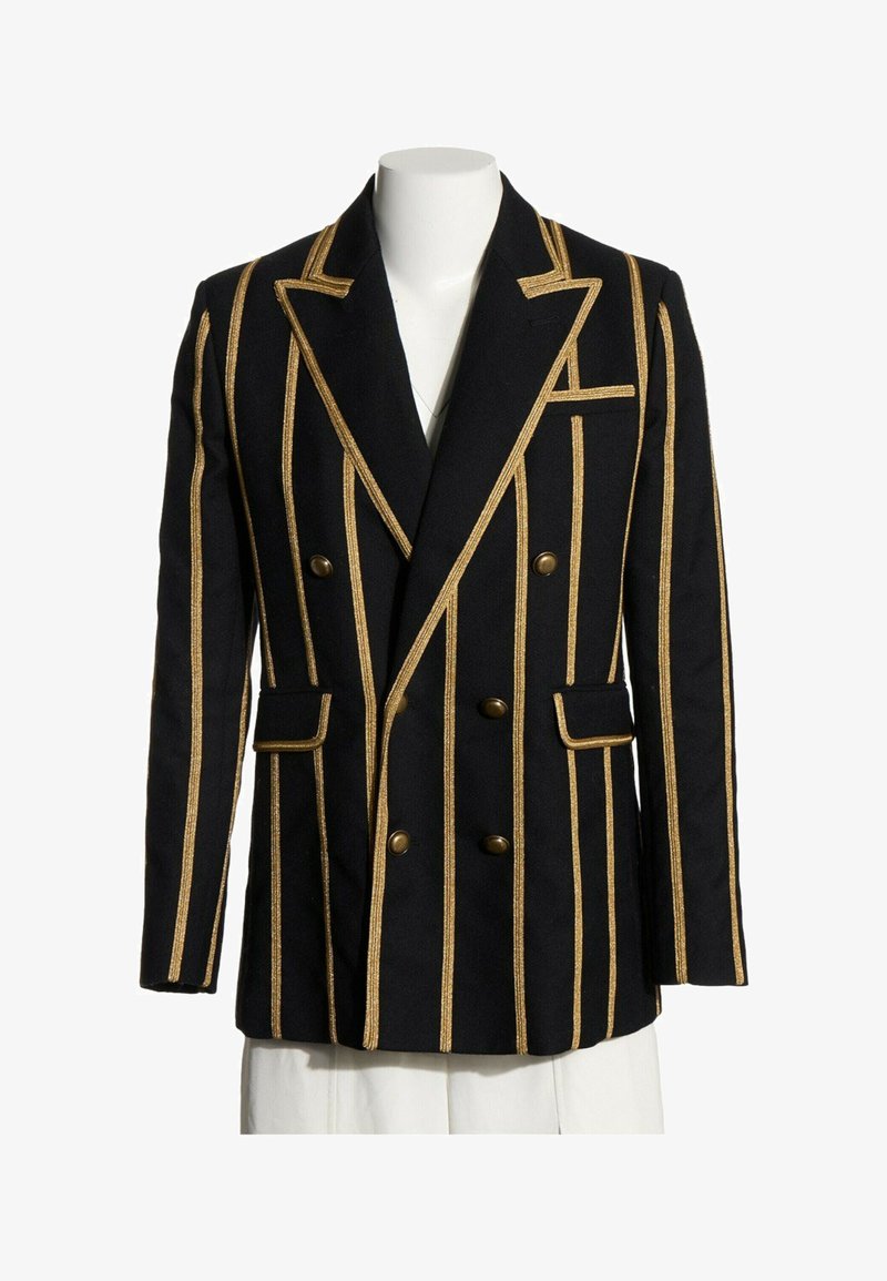 Blazer noir croisé avec des rayures verticales dorées, garniture dorée assortie sur les revers et les poches, et boutons en laiton sur le devant.