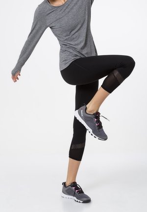 Haut gris à manches longues, leggings capri noirs avec accents en résille, et chaussures de sport grises avec détails roses et semelles blanches.