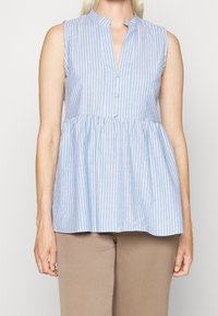 Haut sans manches rayé bleu et blanc avec col mandarin et patte de boutonnage ; buste ajusté avec un bas de peplum évasé.