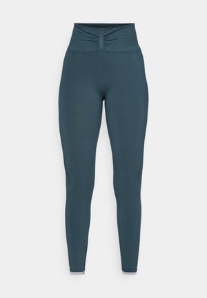 Hoch geschnittene Leggings in einem dunklen Teal-Farbton, mit einem gerafften Detail am Bund und einer glatten Textur entlang des Beins. Keine Muster oder Akzente.