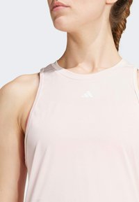 Pink sleeveless athletic top made of smooth fabric, featuring a round neckline and a small white brand logo on the chest.