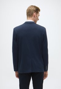 Blazer azul-marinho, design de um só botão, tecido liso, colarinho com cortes, fecho de dois botões, mangas longas com punhos abotoados, costas com abertura.