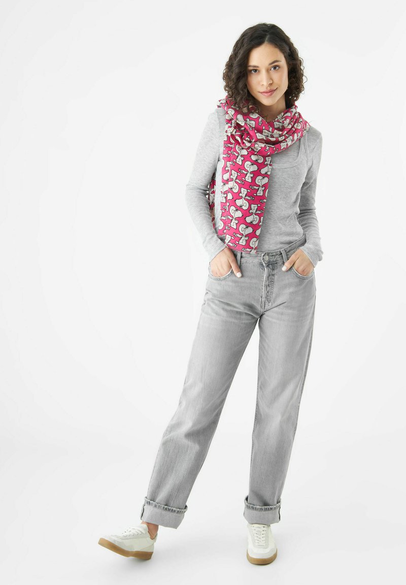 Écharpe rose avec motif animal, portée sur un haut gris à manches longues. Jean large gris clair avec ourlets roulés et baskets blanches.