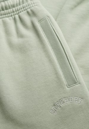 Lichtgroene sweatpants van zacht materiaal, met een ribbelzijdige zak en geborduurd "SUPERDRY" logo in het wit.