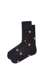 Sorte crew socks med gentagne små hundeansigtter iført røde tørklæder mønstret på stoffet.