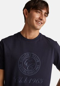 Granatowa koszulka bawełniana z okrągłym nadrukiem graficznym z napisem "Colors Club" oraz "Established 1965" w kontrastowych odcieniach z przodu.