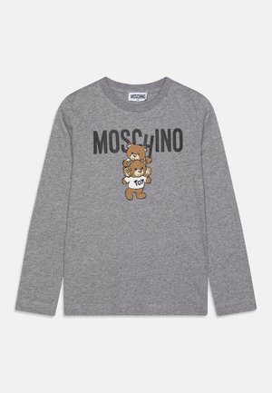 Camiseta gris de manga larga con dos ositos de peluche, uno lleva una camiseta blanca con la palabra "Toy" y encima de los ositos está el texto "MOSCHINO".