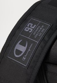 Black fabric patch featuring the Champion logo, the number 92, and text reading "AUTHENTIC ATHLETIC WEAR EST. 1919," with visible stitching.