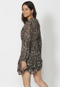 Schwarzes Blumenkleid mit Rüschensäume, durchsichtigen langen Ärmeln und lockerer Passform. Verfügt über mehrfarbige Blumenmuster auf einem strukturierten Stoff.