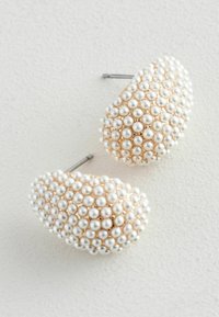Orecchini con perle bianche e accenti dorati, caratterizzati da un design arrotondato e testurizzato, con accessori in tonalità oro e un perno lucido in argento.