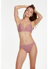 Bikini set u crveno-bijelim geometrijskim uzorcima. Gornji dio ima duboki V-izrez i debele naramenice; donji dio je klasičnog niskog struka.