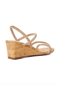 Wedge sandal with a cork sole, beige textured bands with sparkling accents, and a minimalist strappy design.