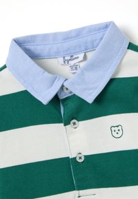 Camisa polo a rayas verdes y blancas con un cuello azul claro. Presenta un emblema de un oso y cierre de botones con costura de botones en contraste.