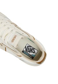 Sneaker Vans in crema con tela strutturata, un accento marrone vicino al tallone e un logo bianco e nero sulla soletta. Design con lacci.