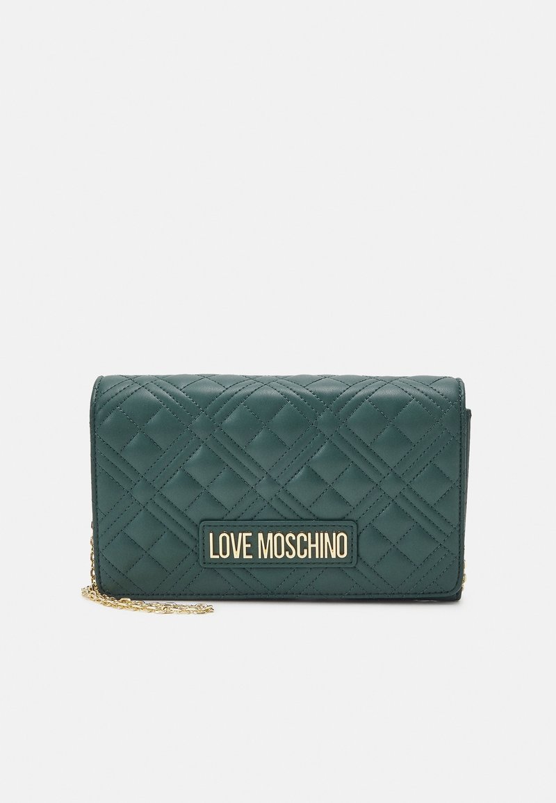 Zielona portmonetka z pikowanej sztucznej skóry, z logo w złotym kolorze i łańcuszkowym paskiem. Cechuje się wyraźnie zarysowanym kształtem i teksturowaną powierzchnią.