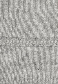 Grå stickad tyg med en strukturerad yta, med en horisontell rad av små vita stygn för ytterligare detalj. Enkel och enhetlig.